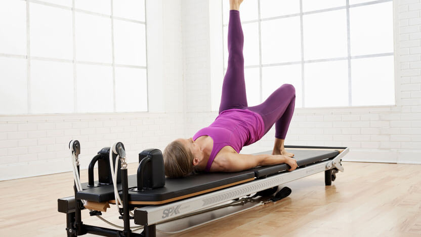 A woman practices Pilates on the Merrithew SPX Max Reformer