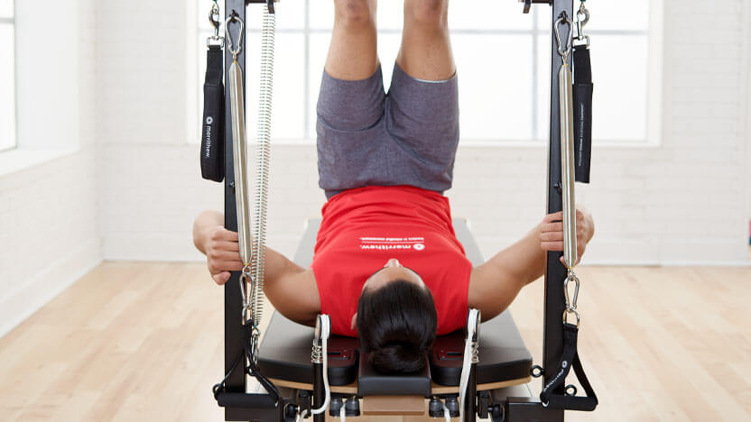 A male home fitness enthusiast practices Pilates on the V2 Max Plus Reformer from Merrithew 