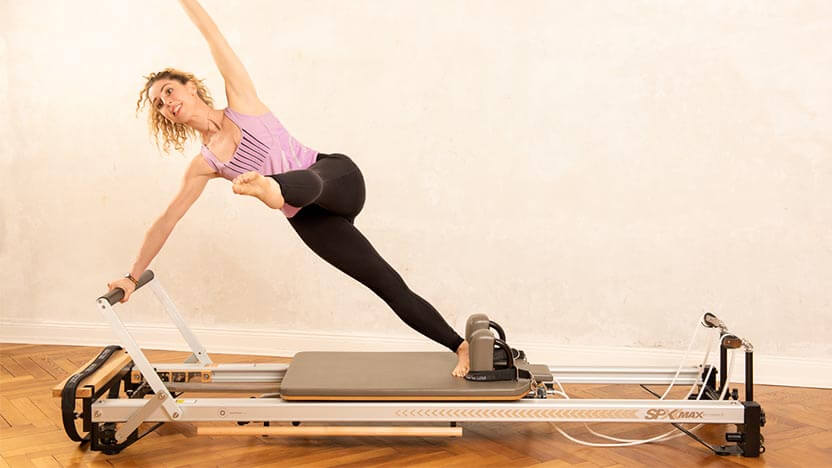 A female Pilates instructor practices a Pilates exercise on the SPX Max Reformer at her studio in Germany