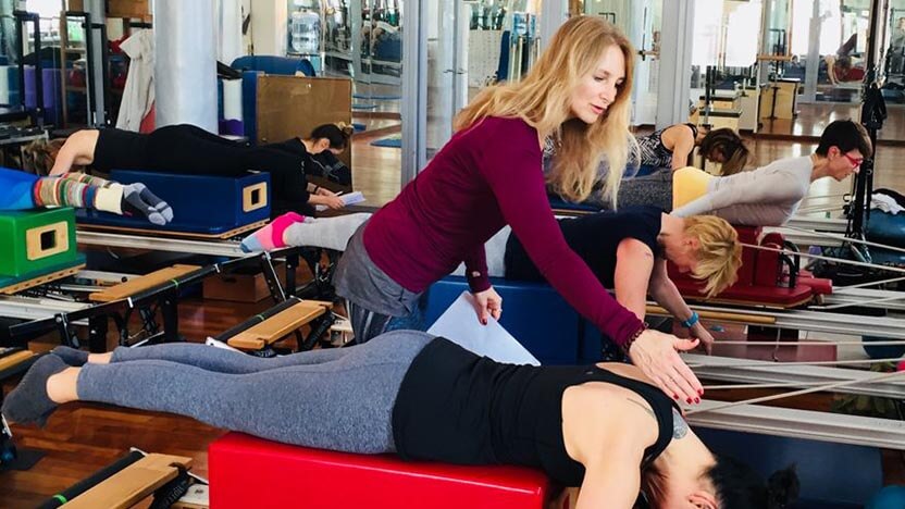 A Pilates instructor at a studio in Munich, Germany assists a student with an exercise on the Pilates Reformer