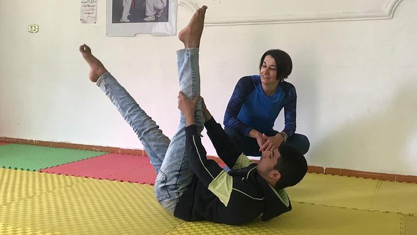 A STOTT PILATES instructor teaches Pilates to a Syrian refugee boy in Jordan