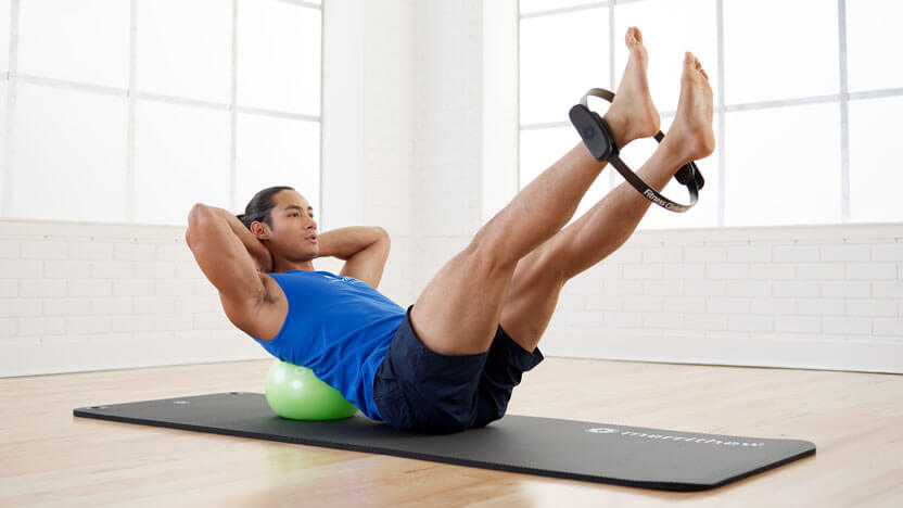 A man practices mat Pilates exercises with the Merrithew Fitness Circle